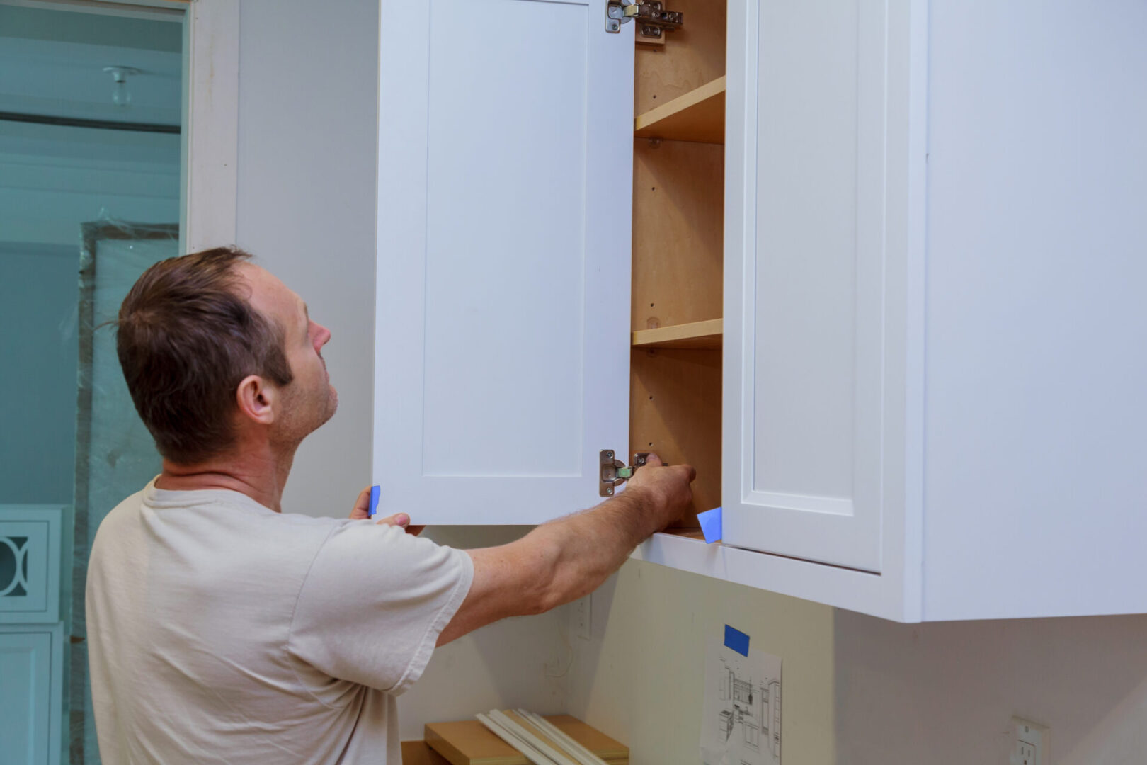 A man is putting some cabinets on the wall